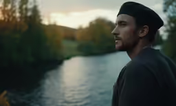 a man standing by the water in the forest