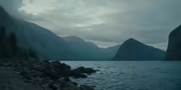 the mountains and water are covered in fog