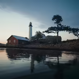 a red house with white top standing on the side of a lake