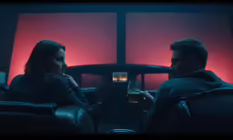 man and woman sitting in chairs next to windows in the dark