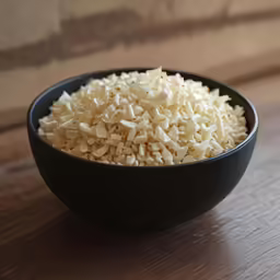 a bowl full of shredded white cheese on a wooden surface