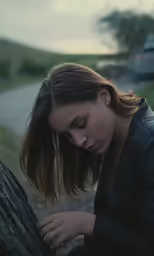 woman with a hand on a tree and eyes closed