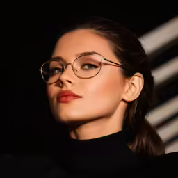 a beautiful young woman wearing glasses and looking to the side