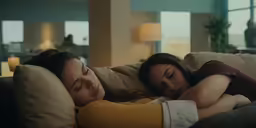 two women are relaxing on a couch with pillows