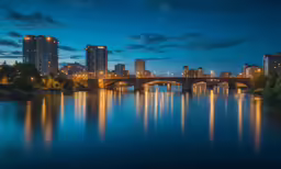 a city skyline at night with a bridge and a body of water