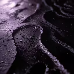 a black water covered road with some small drops