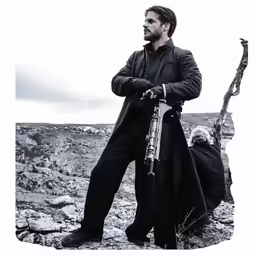a man is holding his bag and standing on top of a hill