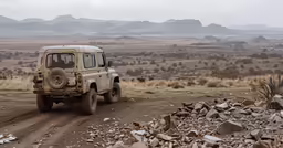 a jeep drives down the road near a rock wall