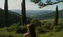 a girl with her back turned looking over to mountains