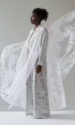 a woman wearing white is standing in front of a large white piece of furniture