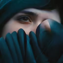 a woman wearing black gloves covering her face