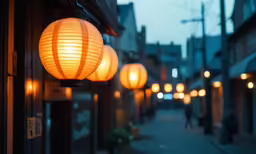 the street is lined with lit lanterns and the person is walking
