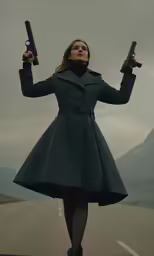 a woman holding two guns and standing on a road