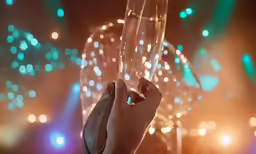 a hand holding an empty glass in front of some lights