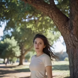 a woman standing under a tree in the park