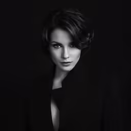 a woman with an open shoulder shirt on, wearing a black suit