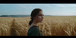 a girl stands alone in the middle of a wheat field