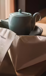 an old fashioned tea pot and a tea bag on a table