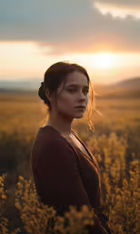 a woman standing in a field with the sun behind her