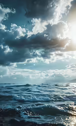 a cloudy sky over the ocean with small waves