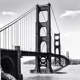 a long bridge spanning across a river next to a hill