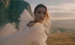a woman in white is standing in the field