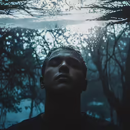 a man is under water while he stares up at trees
