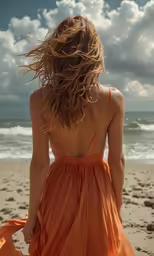 a woman walking along the beach wearing a dress