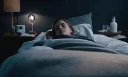 a person in bed under a blanket while listening to her phone