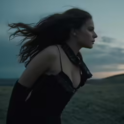 a woman with long, brown hair walks through a field