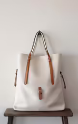 the front view of a white bag with a brown leather trim on it