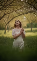 woman praying in grass field during daytime