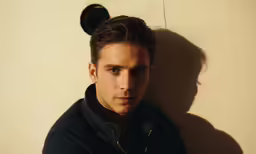a young man looking pensive against a wall