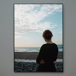 a lady looking at the ocean under a sky filled with clouds