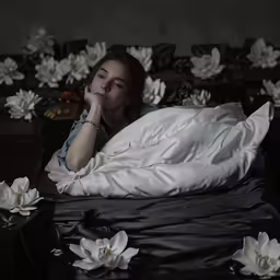 a woman is laying in bed under the covers and flowers
