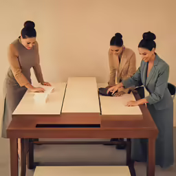 three asian women working on a table with a tabletop