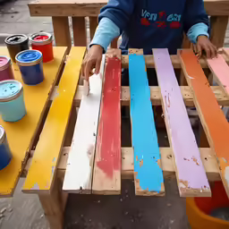a person painted different colors on a bench