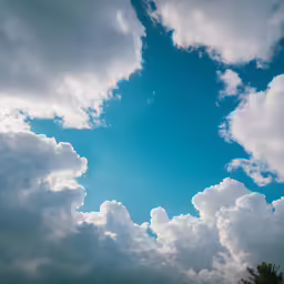 some clouds are in the blue sky and a tree