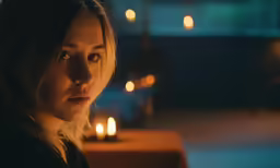 a woman looks on with candles in the background