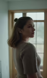 a girl in a gray dress standing next to the window