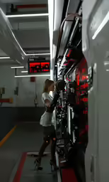 a woman stands inside a parking garage as she checks something on the monitor screen