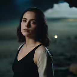 a woman in a black dress staring at the camera