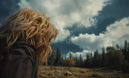 a girl with blonde hair looking up into the sky
