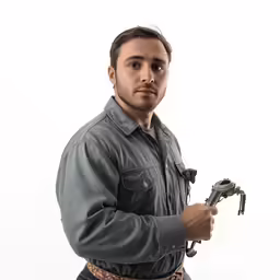 man in a gray shirt and jeans with a wrench