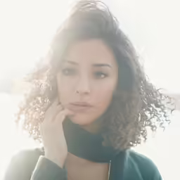 woman with short curly hair wearing a scarf posing for a picture