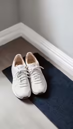 a pair of white tennis shoes sitting on a blue and white mat