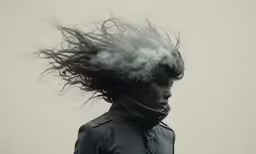 a woman wearing a black leather jacket with a messy hat on her head
