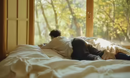 a person laying in bed looking out of a window