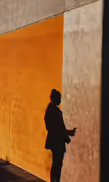 a shadow of a woman walking by a yellow building