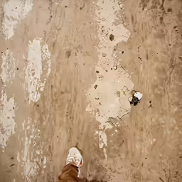 a person standing near a wall with torn paint